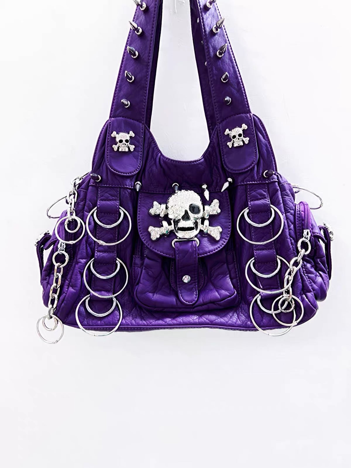 Front detail of purple bag with large skull and crossbones hardware and hanging rings