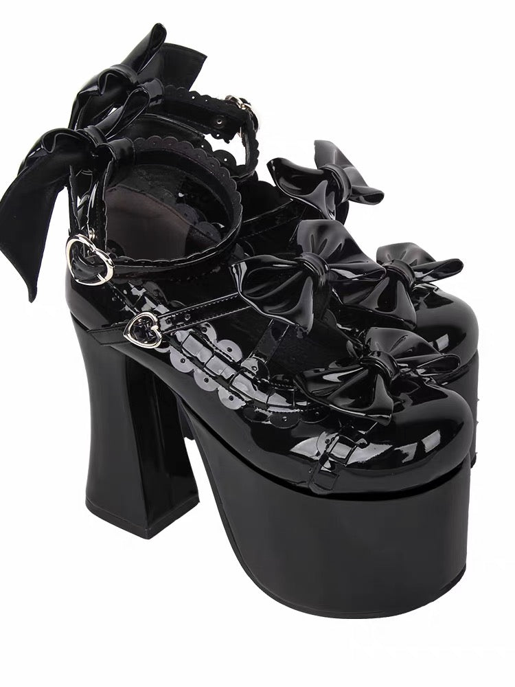 Pair of black glossy platform heels with multiple bows