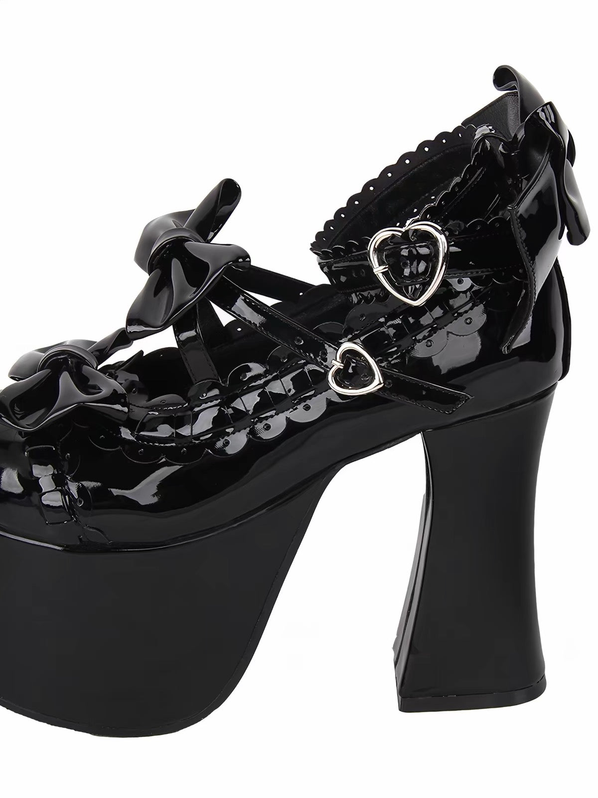 Side detail of black glossy platform heels with heart buckles and bows