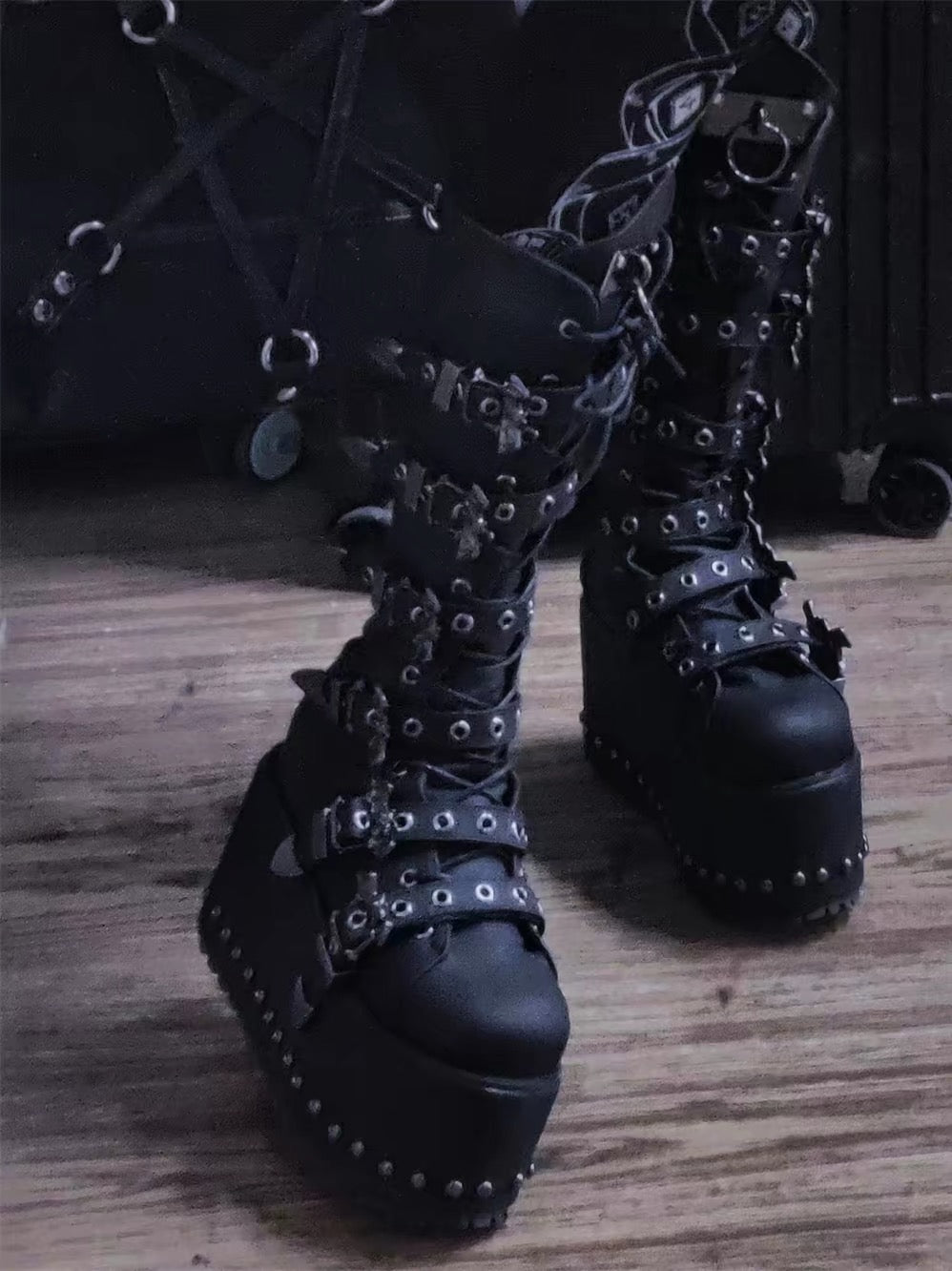 Black knee-high extreme platform boots worn with multiple buckle straps and thick platform soles
