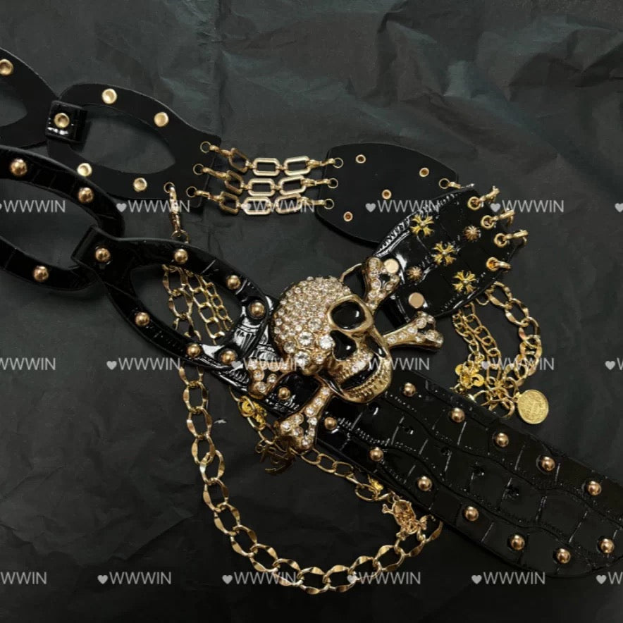 Close-up of black belt with gold skull centerpiece, studs, and chains