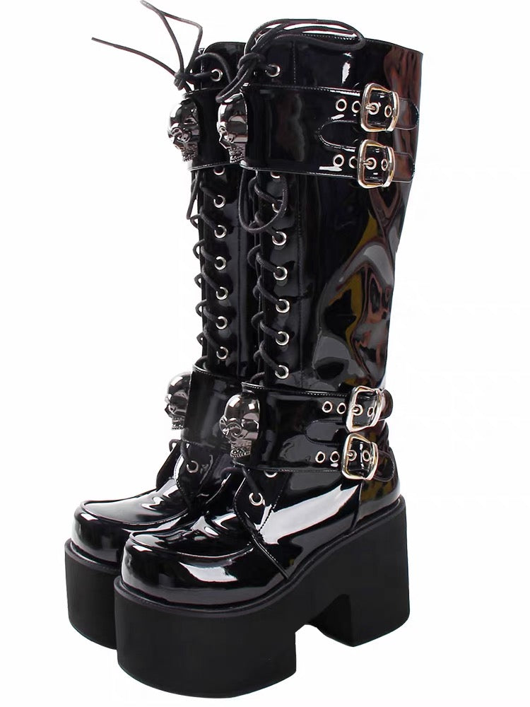 Black patent knee-high platform boots with skull buckle details