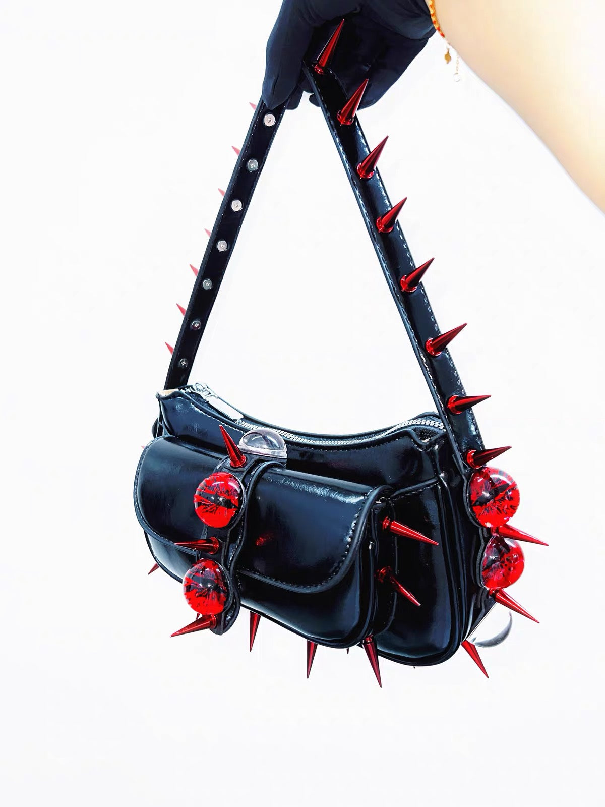 Black patent shoulder bag with red spikes side view
