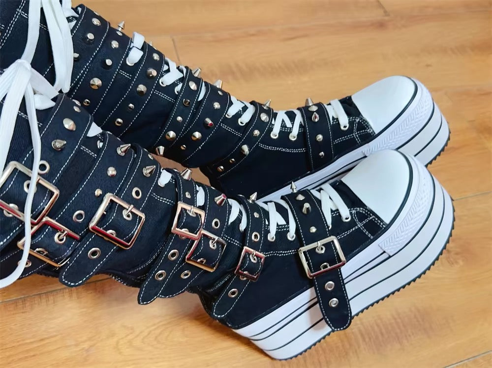 Detail view of black and white platform boots with layered buckle straps and spike hardware