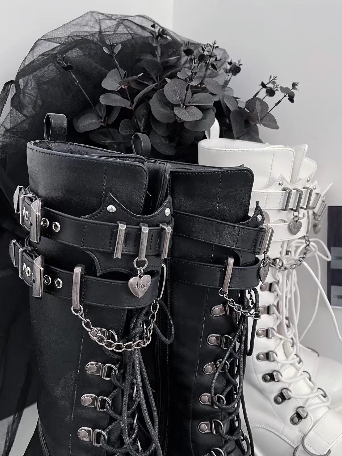Close-up of black and white platform knee-high boots with buckle and chain details