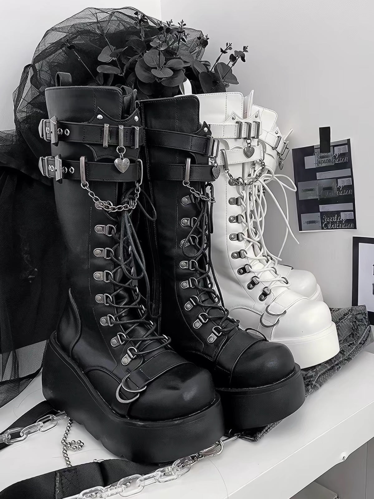 Black and white platform knee-high boots with buckles and chains