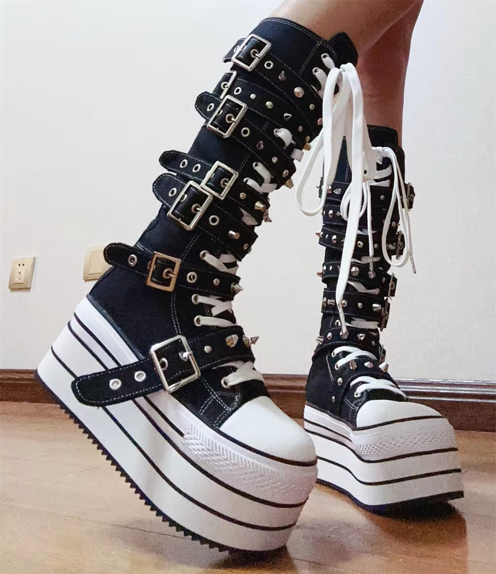Low angle view of black and white knee-high platform boots with silver buckles and studs