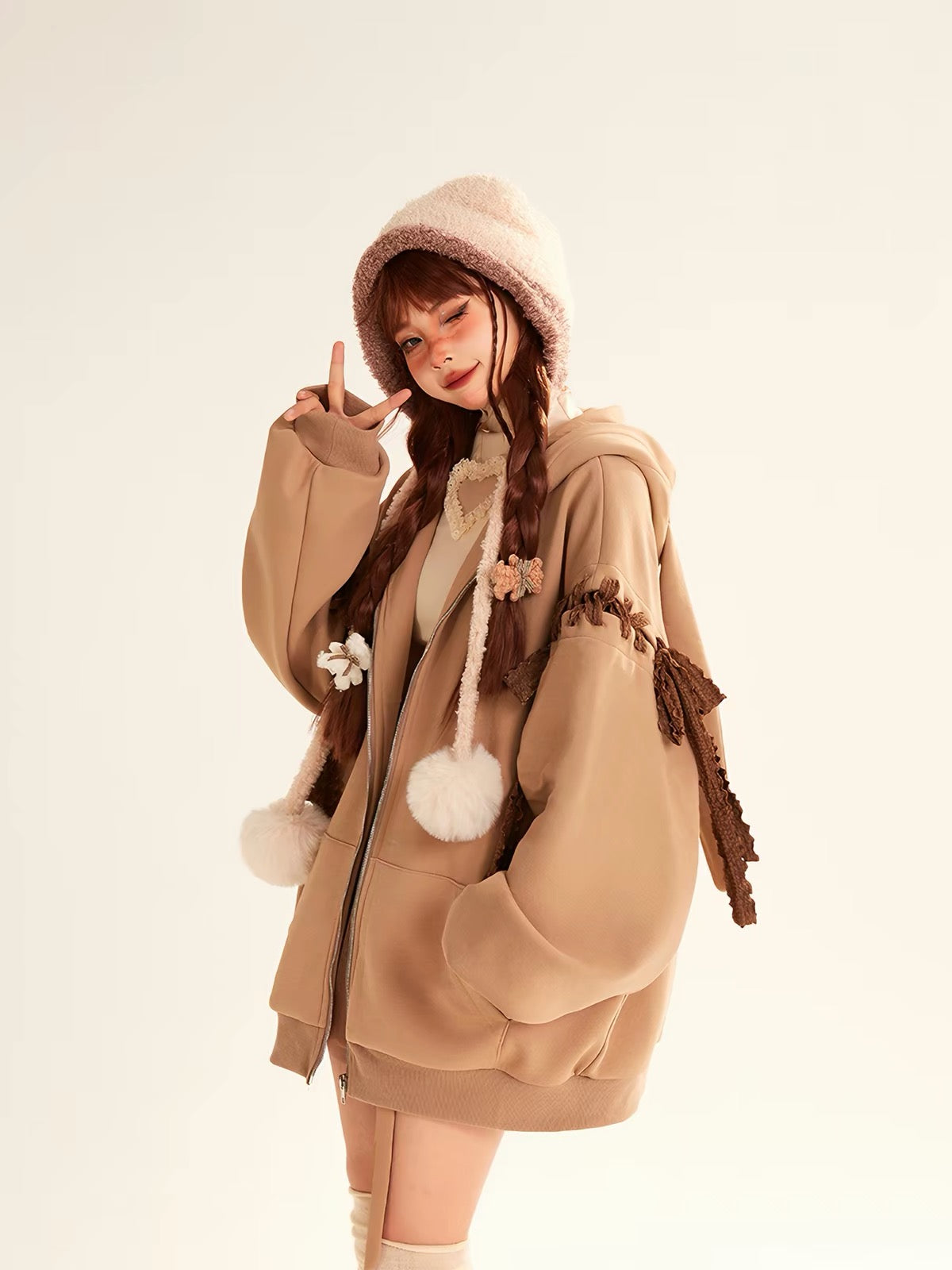 Brown oversized hoodie with decorative bows and pom-pom hood ties