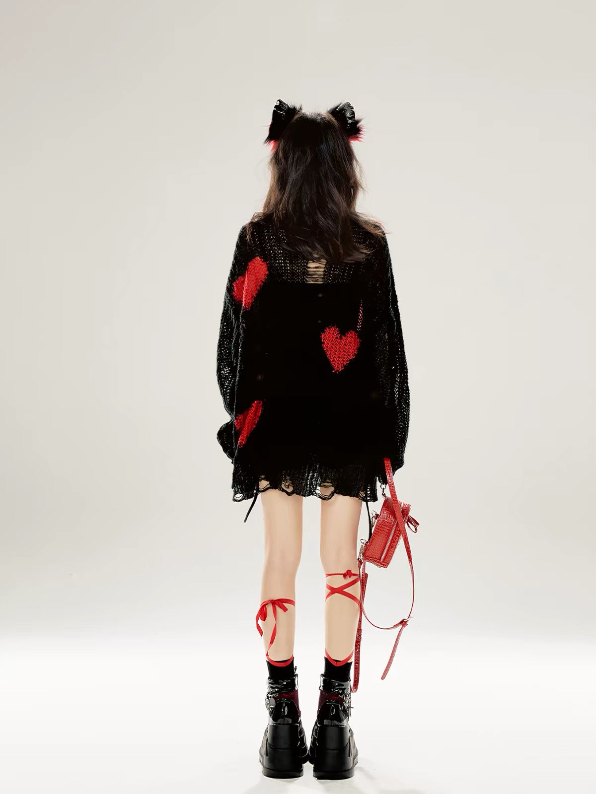 Back view of black distressed knit sweater with red hearts