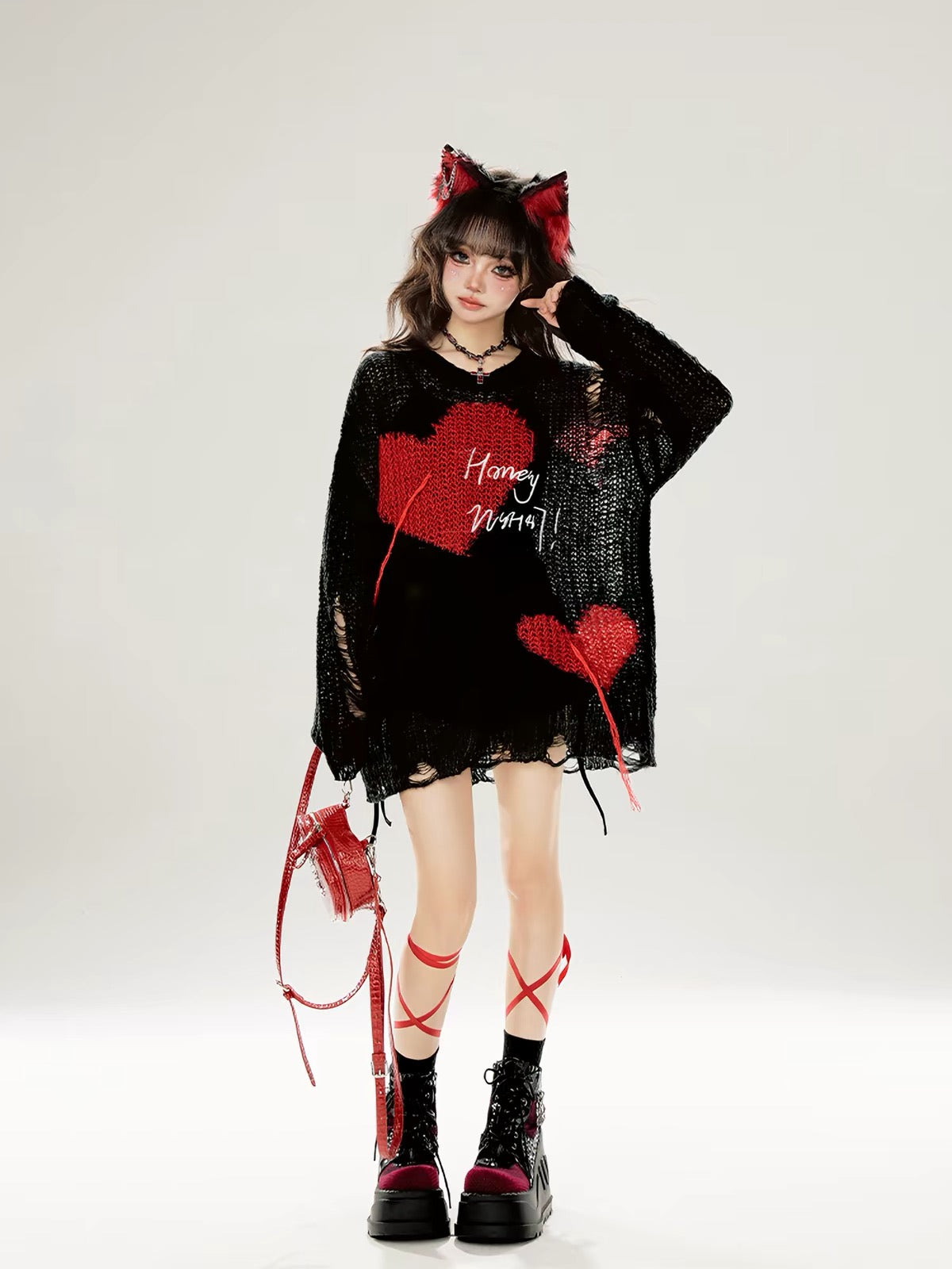 Black oversized distressed knit sweater styled with red accessories