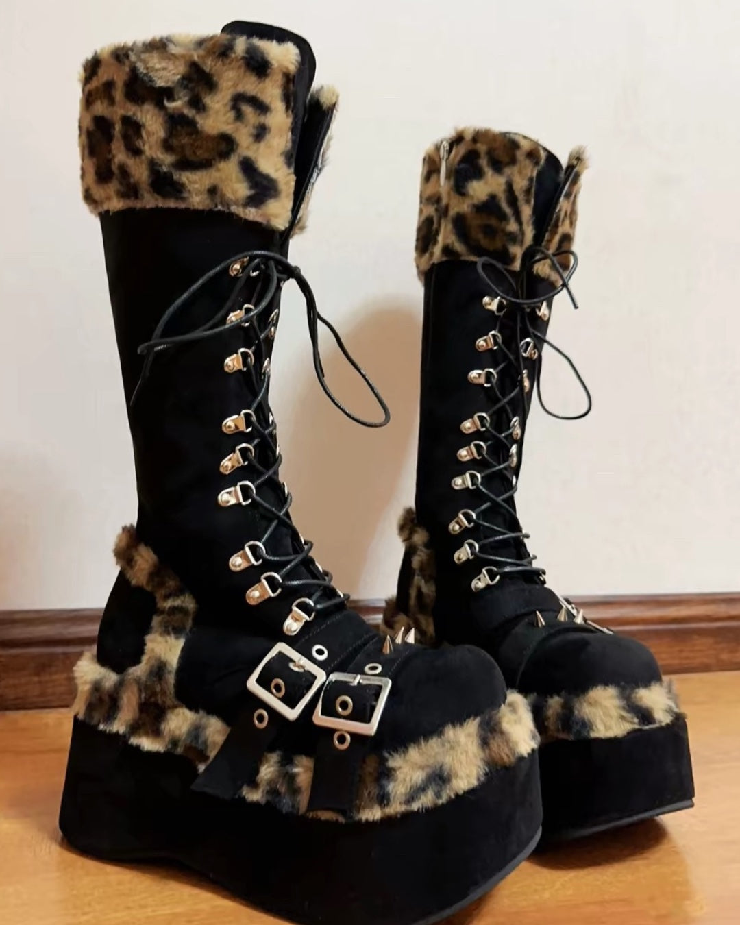 Black knee-high platform boots with leopard faux fur trim, buckles, lace-up front and spikes