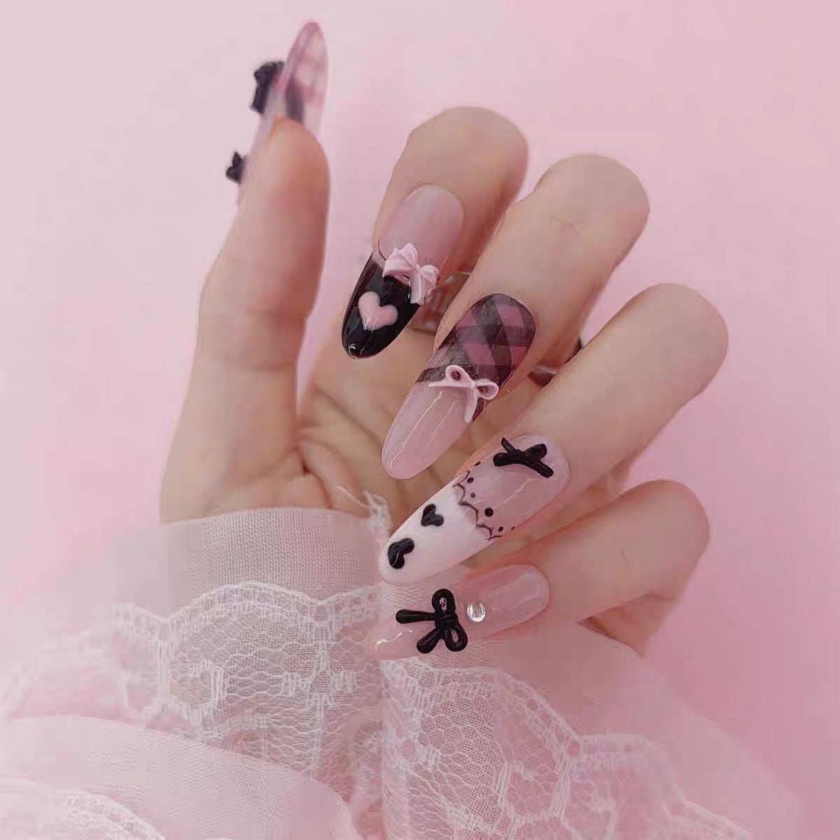 Pink and black bow press-on nails worn on hand