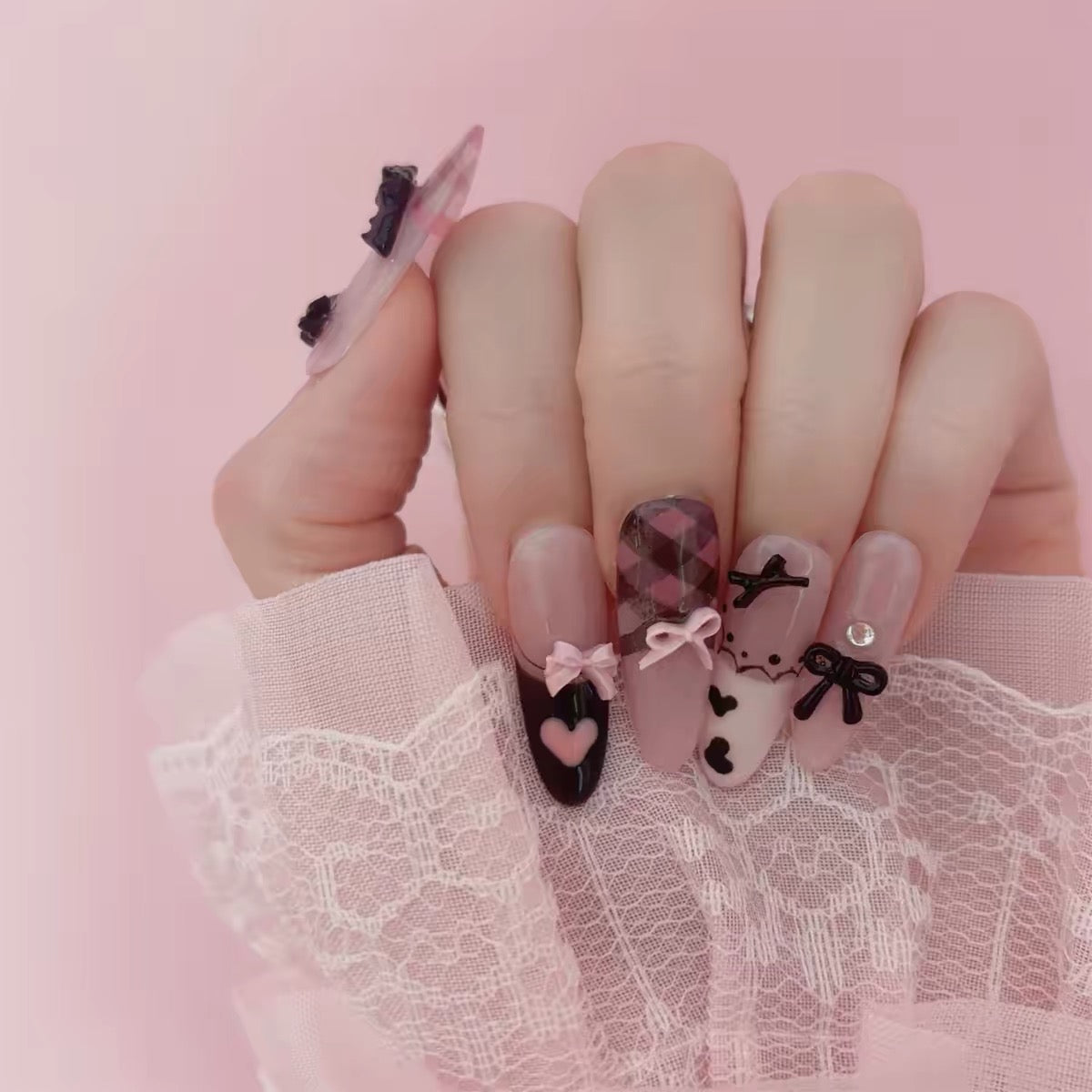 Pink and black bow press-on nails hand view