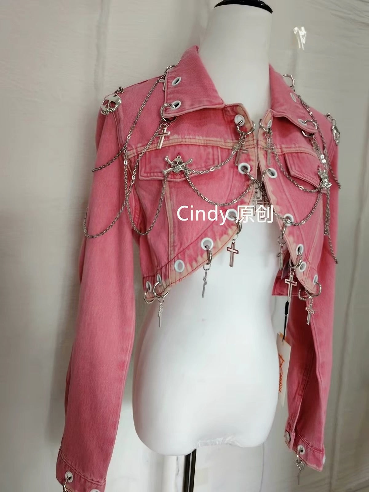 Pink cropped jacket with silver chains, crosses, skull charms and eyelet details