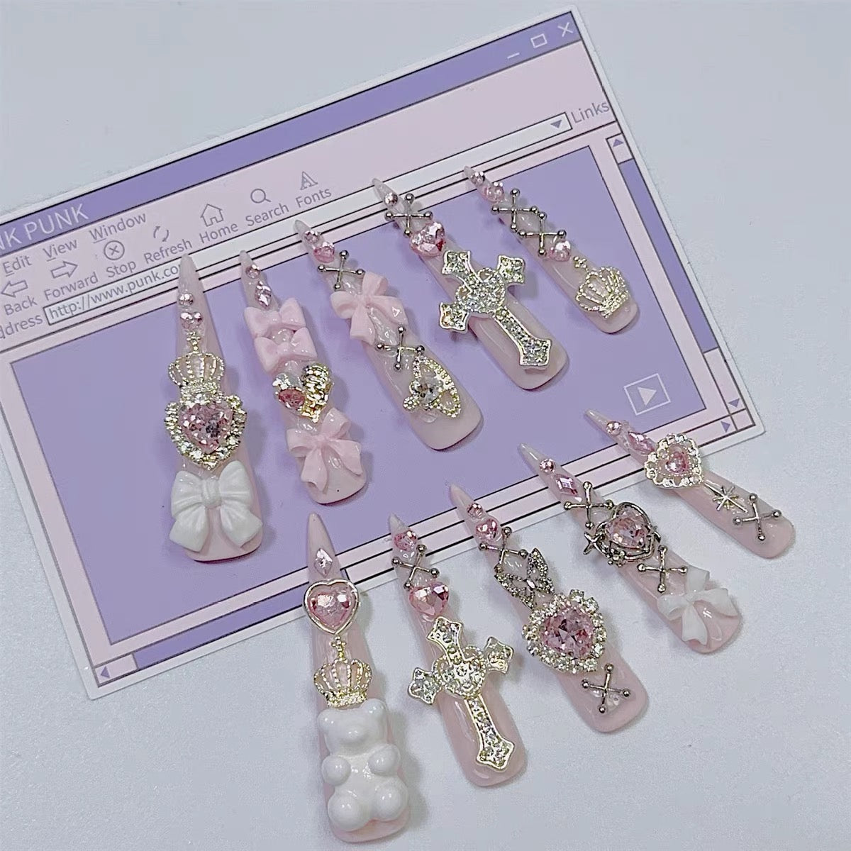 Pink jeweled press-on nails styled on pastel background