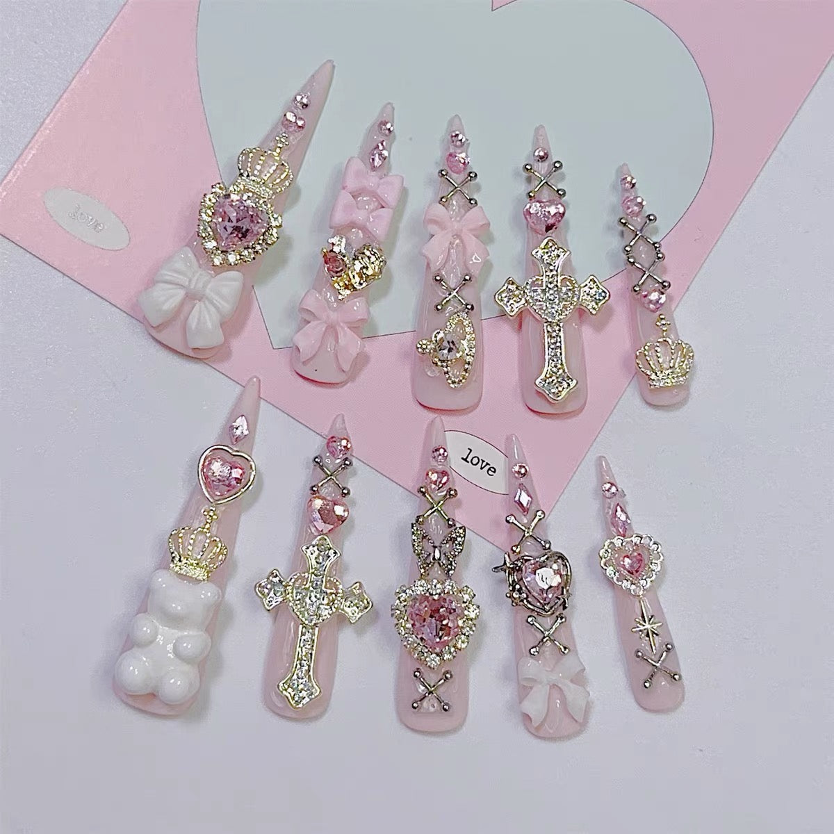 Pink jeweled press-on nail set with cross, heart, crown, bow and rhinestone details