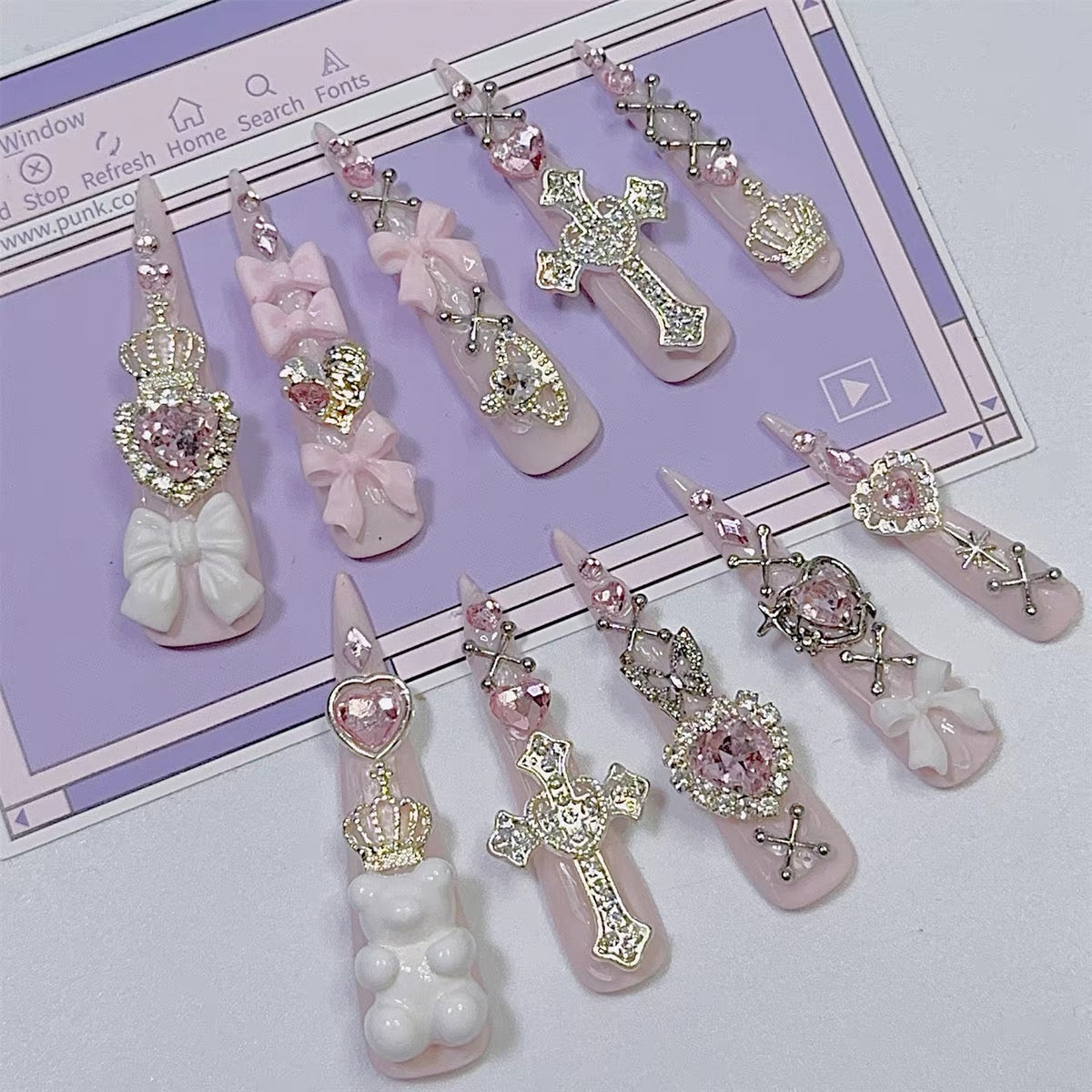 Close-up of pink jeweled press-on nails with silver-tone charms and rhinestones