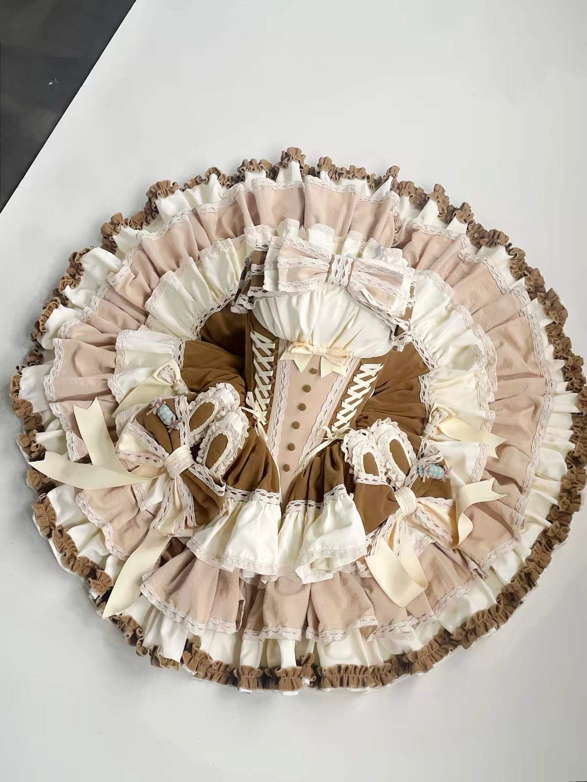 Cream and brown Lolita dress laid flat showing voluminous tiered skirt and corset bodice
