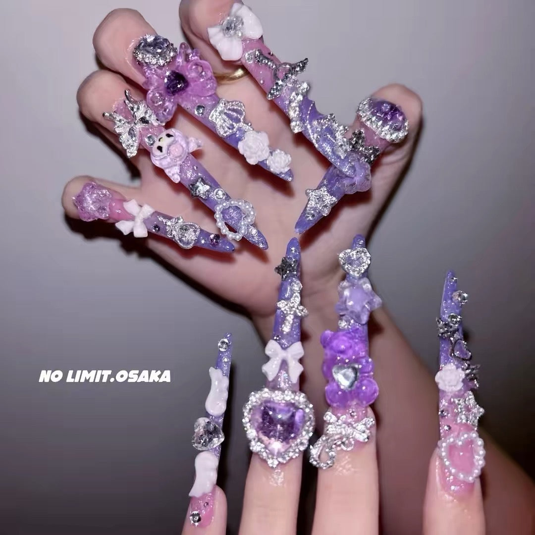 Purple and pink 3D press-on nails with bows, gems, hearts, and floral charms