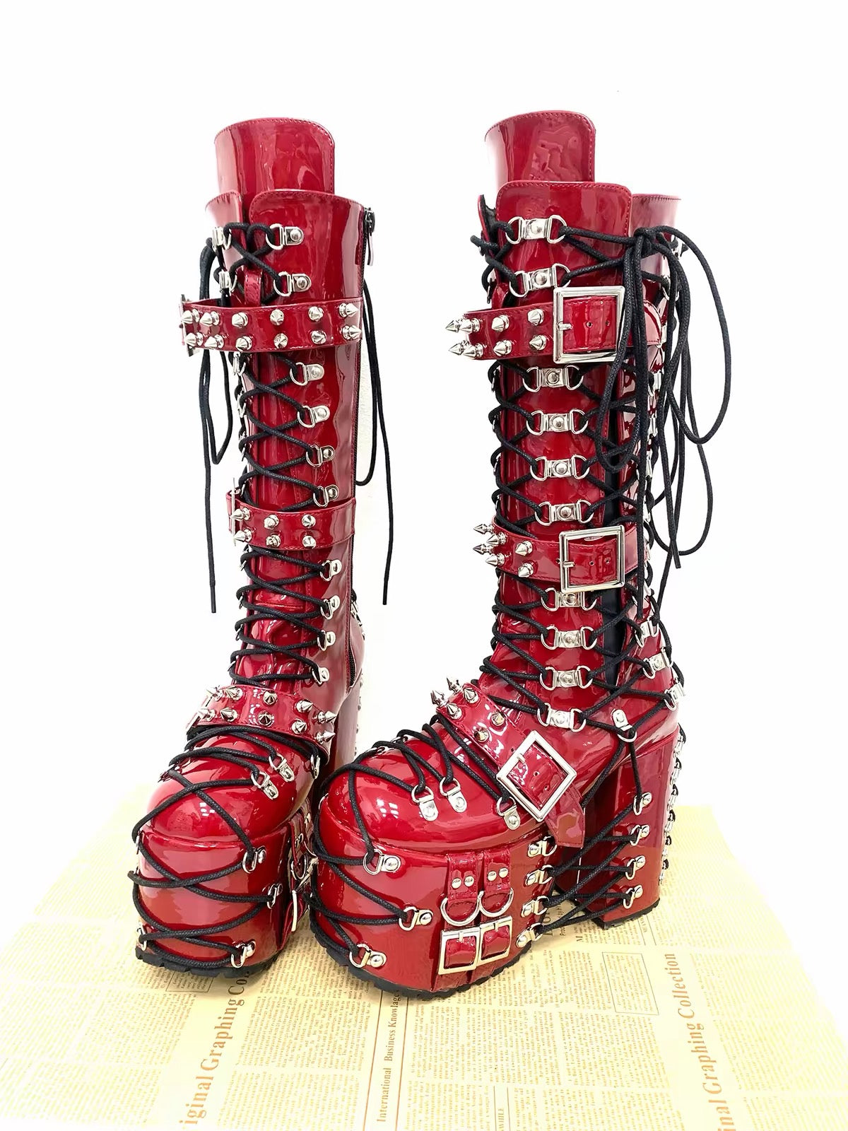 Red knee-high platform boots with lace-up detailing and spike straps
