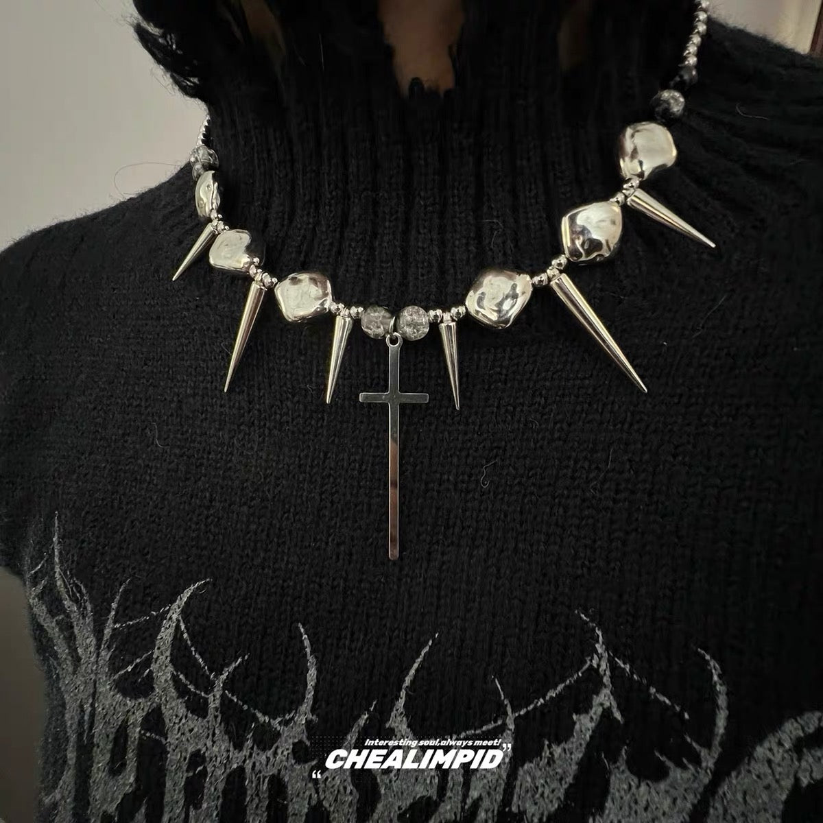 Silver-tone spike and cross necklace worn over black top