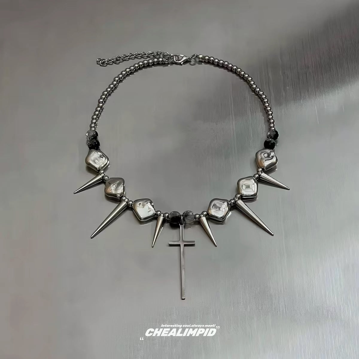 Silver-tone spike and cross necklace laid flat