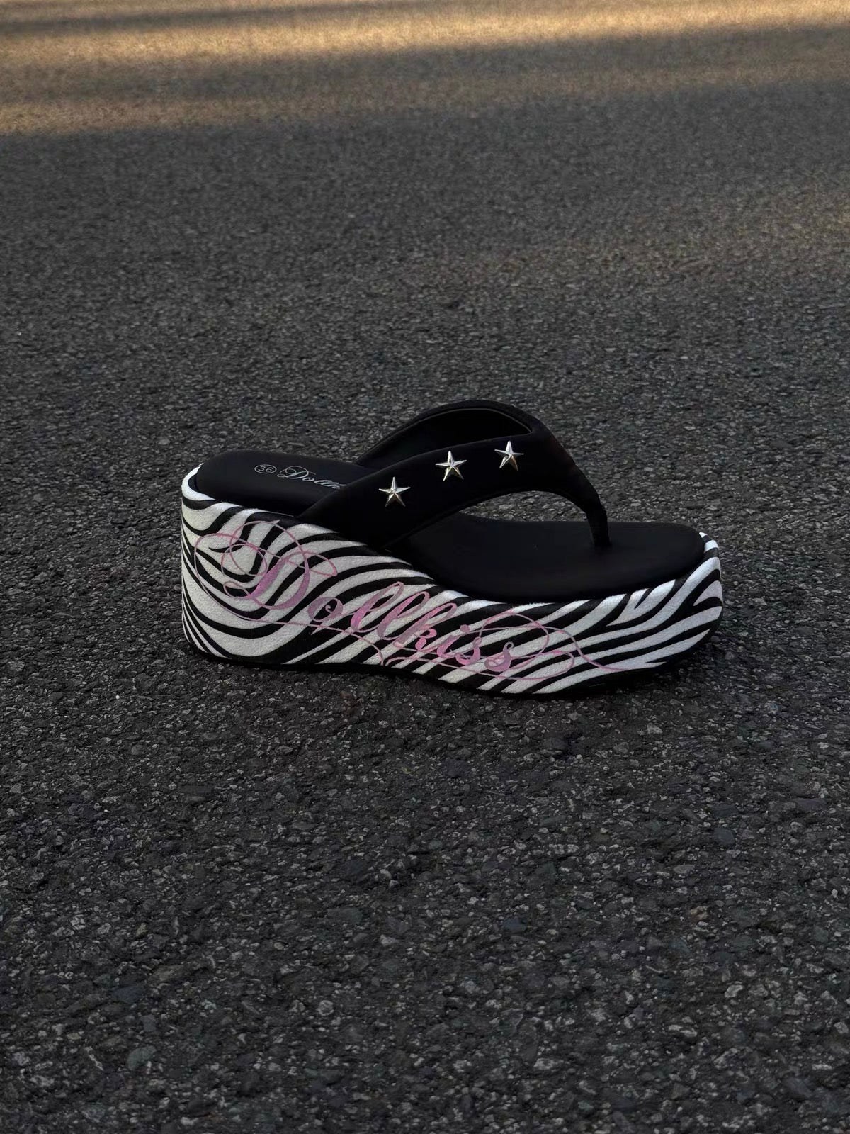 Side view of zebra platform thong sandals with star studs